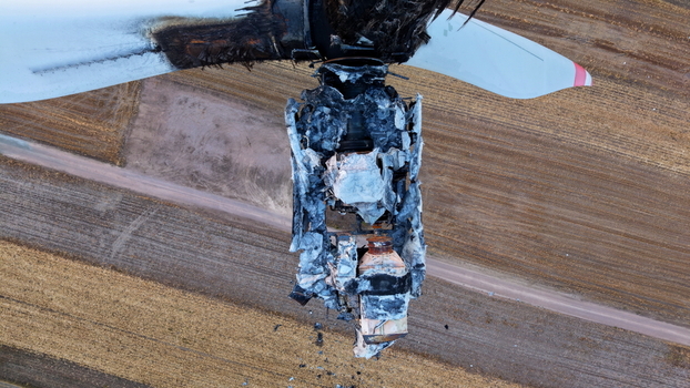 Aerial view of the destroyed wind turbine nacelle with charred metal and mechanical components exposed above agricultural fields in Vladimirovac Vojvodina Serbia.