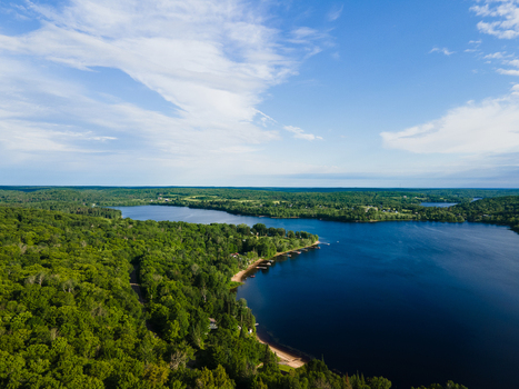 Aerial view of Commanda Lake surrounded by dense green forests and calm blue waters under a clear summer sky in Restoule Ontario Canada. Aerial view of Commanda Lake surrounded by dense green forests and calm blue waters under a clear summer sky in Restoule Ontario Canada.