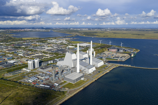 Aerial view of the Avedore Power Station with its tall white chimneys and surrounding industrial facilities along the coast under a cloudy sky Hvidovre Denmark.