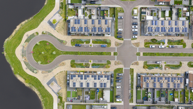 Aerial view of the Nobelhorst neighborhood featuring modern houses with solar panels on rooftops and symmetrical streets next to a canal in Almere Flevoland Netherlands. Aerial view of the Nobelhorst neighborhood featuring modern houses with solar panels on rooftops and symmetrical streets next to a canal in Almere Flevoland Netherlands.