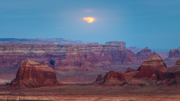 View of the majestic red rock buttes and desert landscape under a glowing moon at dusk Lake Powell Arizona United States. View of the majestic red rock buttes and desert landscape under a glowing moon at dusk Lake Powell Arizona United States.