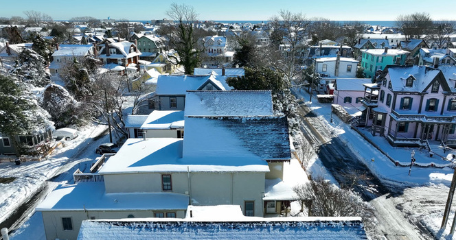 Aerial view of the historic Victorian houses covered in snow on a bright winter day with clear blue sky and snow covered streets in Cape May New Jersey United States.