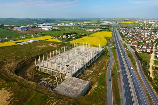 Aerial view of a large concrete building frame under construction next to a highway and yellow canola fields in Silivri Istanbul Turkey. Aerial view of a large concrete building frame under construction next to a highway and yellow canola fields in Silivri Istanbul Turkey.