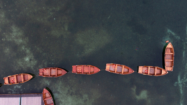 Aerial view of wooden rowboats moored in a line on the clear turquoise waters of Pragser Wildsee in Prags Trentino Alto AdigeS Italy.