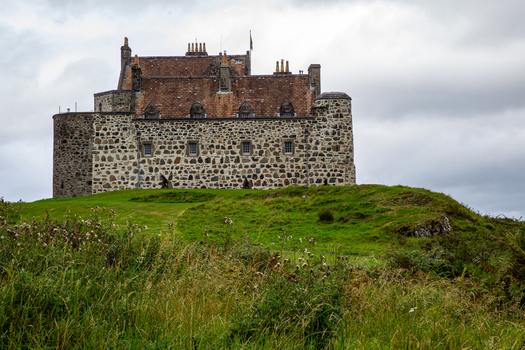 View of Duart Castle a historic stone fortress standing on a grassy hill under a cloudy sky in Isle of Mull Scotland United Kingdom.