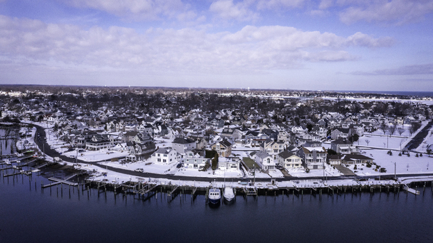 Aerial view of the coastal town of Manasquan covered in snow during winter featuring residential houses a waterfront with boat slips and calm water in Manasquan New Jersey United States. Aerial view of the coastal town of Manasquan covered in snow during winter featuring residential houses a waterfront with boat slips and calm water in Manasquan New Jersey United States.
