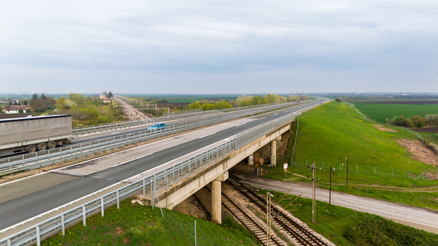 Aerial view of the highway stretching towards the horizon amidst the green fields and cloudy sky Sremska Mitrovica Vojvodina Serbia. Aerial view of the highway stretching towards the horizon amidst the green fields and cloudy sky Sremska Mitrovica Vojvodina Serbia.