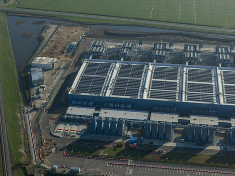 Aerial view of an ai data center with cooling towers and a cloud computing hub exterior near green fields. Aerial view of an ai data center with cooling towers and a cloud computing hub exterior near green fields.