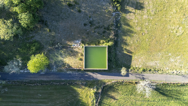 Aerial view of a square green water tank next to a rural road surrounded by lush fields and trees in Ourense Province of Ourense Spain. Aerial view of a square green water tank next to a rural road surrounded by lush fields and trees in Ourense Province of Ourense Spain.