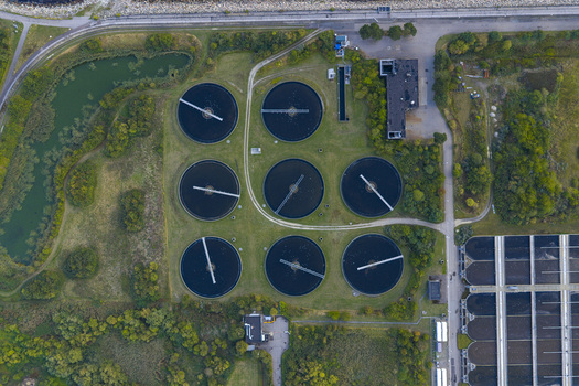 Aerial view of circular sedimentation tanks at a wastewater treatment plant surrounded by green vegetation and industrial buildings in Hvidovre Denmark. Aerial view of circular sedimentation tanks at a wastewater treatment plant surrounded by green vegetation and industrial buildings in Hvidovre Denmark.