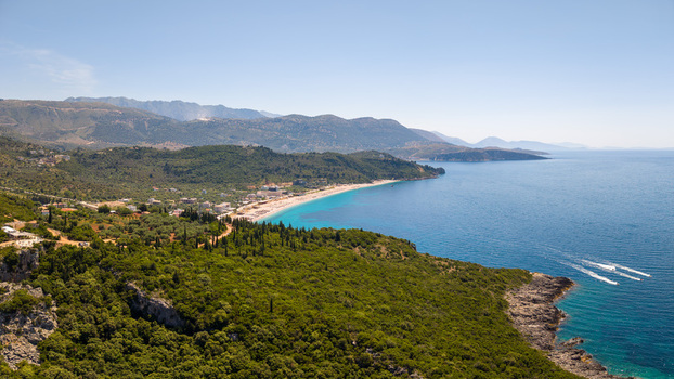 Aerial view of the turquoise waters of the Ionian Sea lush green hills and the sandy coastline near Aquarium Beach in Jala Vlore County Albania.