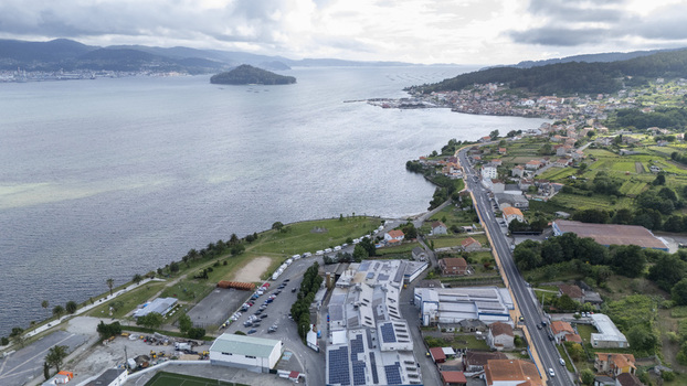Aerial view of the coastal town of Casalvito featuring industrial buildings with solar panels along the bay and green hills under a cloudy sky Casalvito Pontevedra Spain. Aerial view of the coastal town of Casalvito featuring industrial buildings with solar panels along the bay and green hills under a cloudy sky Casalvito Pontevedra Spain.