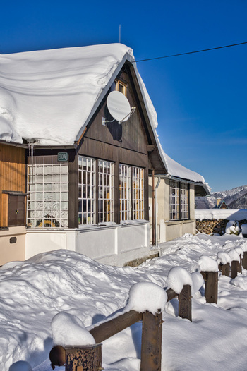 View of a snow dusted wooden chalet with a satellite dish stands against a vibrant blue sky encased in a thick blanket of winter Donovaly Banskobystricky kraj Slovakia. View of a snow dusted wooden chalet with a satellite dish stands against a vibrant blue sky encased in a thick blanket of winter Donovaly Banskobystricky kraj Slovakia.