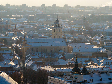 Aerial view of the snow covered rooftops and the Church of St. Johns in the historic old town under a hazy winter sky in Vilnius County Lithuania.