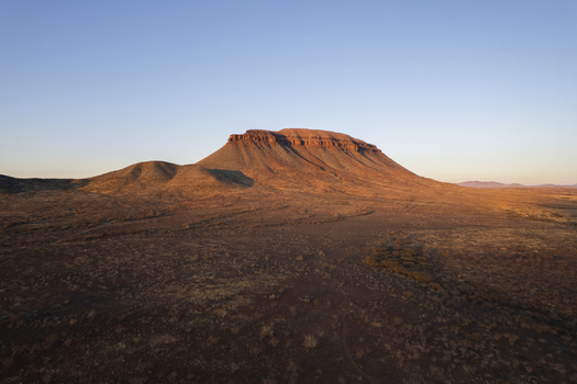 Aerial view of a flat topped mountain bathed in the warm glow of the setting sun casting long shadows across the arid landscape Namibia. Aerial view of a flat topped mountain bathed in the warm glow of the setting sun casting long shadows across the arid landscape Namibia.