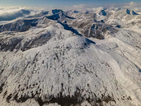 Aerial view of the snow covered peaks and rugged ridges of Babusar Pass under a bright sky with soft clouds Babusar KPK Pakistan. Aerial view of the snow covered peaks and rugged ridges of Babusar Pass under a bright sky with soft clouds Babusar KPK Pakistan.