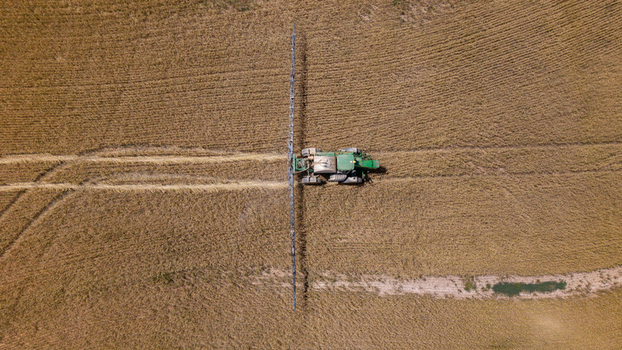 Aerial view of a tractor spraying a large golden wheat field in rural farmland Philadelphia Western Cape South Africa. Aerial view of a tractor spraying a large golden wheat field in rural farmland Philadelphia Western Cape South Africa.