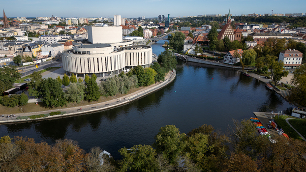 Aerial view of the Opera Nova s modern curves contrasting with the historic red brick church along the dark reflective Brda River Bydgoszcz Województwo kujawsko pomorskie Poland. Aerial view of the Opera Nova s modern curves contrasting with the historic red brick church along the dark reflective Brda River Bydgoszcz Województwo kujawsko pomorskie Poland.
