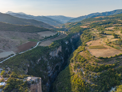 Aerial view of Osumi canyon featuring deep limestone cliffs winding river below surrounding agricultural fields and lush green vegetation in Dhores Berat County Albania.