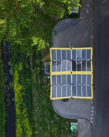 Aerial view of the Fastned Charging Station featuring a solar panel roof next to a green canal and lush vegetation in Vierpolders Zuid Holland Netherlands. Aerial view of the Fastned Charging Station featuring a solar panel roof next to a green canal and lush vegetation in Vierpolders Zuid Holland Netherlands.