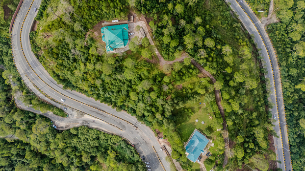 Aerial view of the Islamabad Murree Expressway winding through lush green hills and pine forests with houses with green roofs nestled in the landscape in Lower Topa Punjab Pakistan. Aerial view of the Islamabad Murree Expressway winding through lush green hills and pine forests with houses with green roofs nestled in the landscape in Lower Topa Punjab Pakistan.