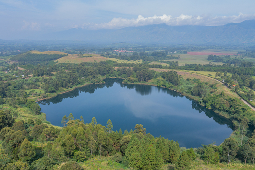 Aerial view of a serene crater lake surrounded by lush green forests and rolling hills in the landscape of Fort Portal Western Region Uganda. Aerial view of a serene crater lake surrounded by lush green forests and rolling hills in the landscape of Fort Portal Western Region Uganda.