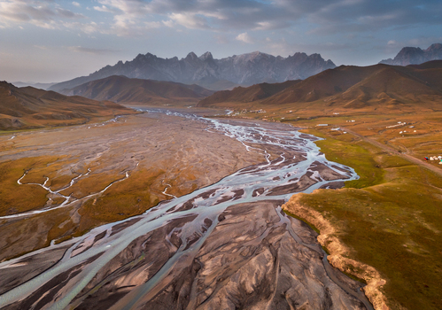 Aerial view of the braided river winding through the vast valley towards rugged mountains in At Bashi District Naryn Region Kyrgyzstan. Aerial view of the braided river winding through the vast valley towards rugged mountains in At Bashi District Naryn Region Kyrgyzstan.