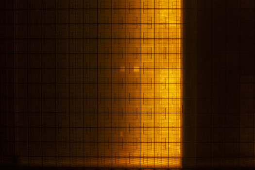 Aerial view of a large greenhouse complex glowing with orange light at night highlighting the geometric grid of the glass structures.