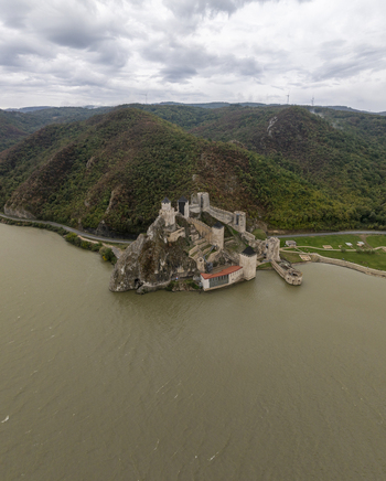 Aerial view of Golubac Fortress on the rocky banks of the Danube River featuring medieval stone walls and towers surrounded by green hills in Golubac Branicevski okrug Serbia. Aerial view of Golubac Fortress on the rocky banks of the Danube River featuring medieval stone walls and towers surrounded by green hills in Golubac Branicevski okrug Serbia.