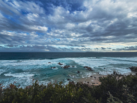 View of the turquoise ocean waves crashing against rocks along the coastline under a dramatic cloudy sky in Plettenberg Bay Western Cape South Africa. View of the turquoise ocean waves crashing against rocks along the coastline under a dramatic cloudy sky in Plettenberg Bay Western Cape South Africa.