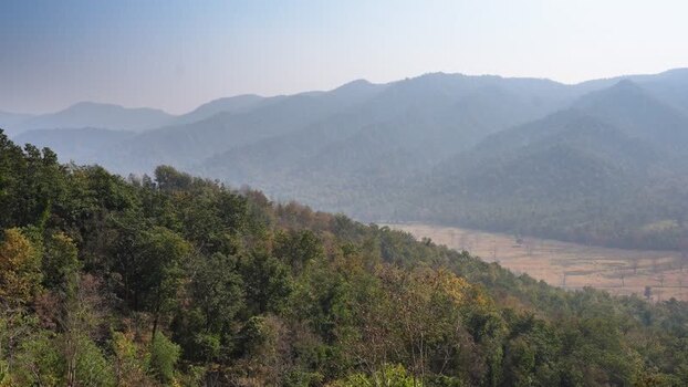 View of lush green forested hills and misty mountains Nepal.
