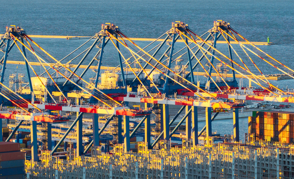 Aerial view of Seaport Container Terminal with large gantry cranes stacked shipping containers and calm harbor waters in Poland.