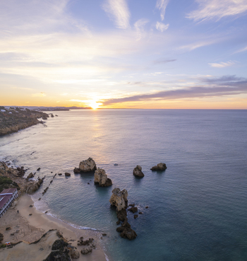 Aerial view of Praia dos Arrifes with its distinctive rock formations rising from the calm sea sandy beach and golden sunset light in Faro District Portugal. Aerial view of Praia dos Arrifes with its distinctive rock formations rising from the calm sea sandy beach and golden sunset light in Faro District Portugal.