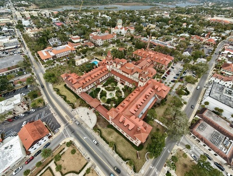 Aerial view of Flagler College featuring its iconic red tiled roofs and Spanish Renaissance architecture surrounded by historic streets and lush greenery in St. Augustine Florida United States.