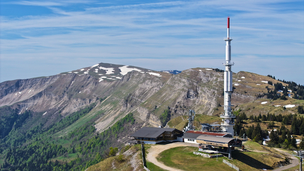 Aerial view of Col de la Faucille featuring the telecommunications tower and snowy mountain ridges under a clear blue sky in Gex Auvergne Rhone Alpes France. Aerial view of Col de la Faucille featuring the telecommunications tower and snowy mountain ridges under a clear blue sky in Gex Auvergne Rhone Alpes France.