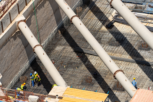 Aerial view of construction workers in safety gear working on a steel rebar foundation with large white support struts in Dubai Dubai United Arab Emirates. Aerial view of construction workers in safety gear working on a steel rebar foundation with large white support struts in Dubai Dubai United Arab Emirates.