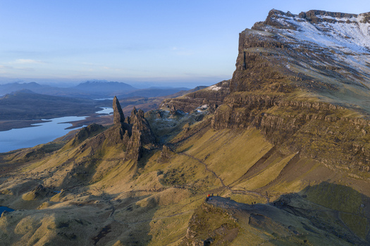 Aerial view of The Storr rock formations with snow dusted peaks and a distant lake under a clear sky Isle of Skye Scotland United Kingdom. Aerial view of The Storr rock formations with snow dusted peaks and a distant lake under a clear sky Isle of Skye Scotland United Kingdom.
