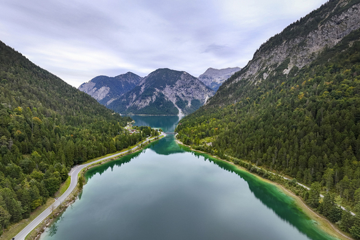 Aerial view of the serene Plansee lake mirroring the sky nestled between verdant forests and towering mountains Reutte Tyrol Austria. Aerial view of the serene Plansee lake mirroring the sky nestled between verdant forests and towering mountains Reutte Tyrol Austria.