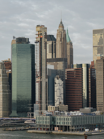 View of the dense New York City skyline featuring modern glass skyscrapers and historic architecture under a cloudy sky in New York New York United States.