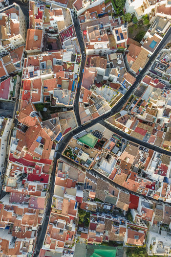 Aerial view of dense red tiled rooftops and narrow winding streets with rooftop terraces and small swimming pools in Sitges Catalonia Spain. Aerial view of dense red tiled rooftops and narrow winding streets with rooftop terraces and small swimming pools in Sitges Catalonia Spain.
