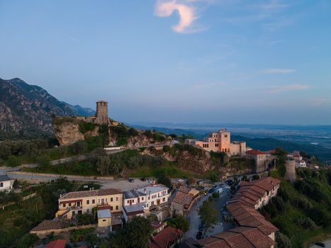 Aerial view of the historic Kruje Castle and old town rooftops nestled against rugged mountains under a clear sky in Kruje Durres County Albania.