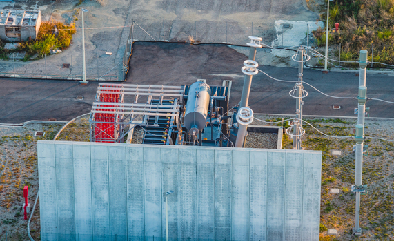 Aerial view of a large power transformer and high voltage equipment protected by a concrete barrier inside an industrial electrical substation in Italy. Aerial view of a large power transformer and high voltage equipment protected by a concrete barrier inside an industrial electrical substation in Italy.