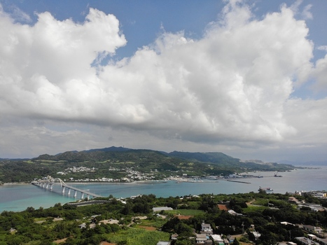 Aerial view of the bridge connecting to Sesoko Island featuring lush green hills turquoise waters and coastal architecture in Motobu Okinawa Japan. Aerial view of the bridge connecting to Sesoko Island featuring lush green hills turquoise waters and coastal architecture in Motobu Okinawa Japan.