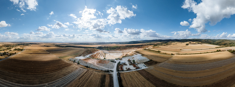 Aerial view of the quarry in Besenovo surrounded by vast agricultural fields and rolling hills under a bright blue sky in Besenovo Vojvodina Serbia.