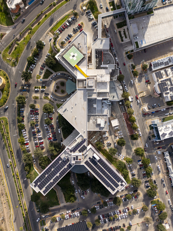 Aerial view of a modern building complex featuring extensive rooftop solar panel arrays surrounded by a busy parking lot and urban streets in Chihuahua Chihuahua Mexico. Aerial view of a modern building complex featuring extensive rooftop solar panel arrays surrounded by a busy parking lot and urban streets in Chihuahua Chihuahua Mexico.
