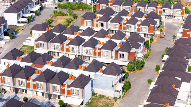 Aerial view of a modern residential housing complex with uniform houses featuring dark roofs and paved streets in Semarang Central Java Indonesia.