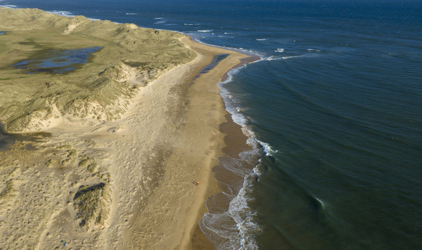 Aerial view of a vast sandy beach and rolling grassy dunes with a person walking along the shore Peterhead Scotland United Kingdom. Aerial view of a vast sandy beach and rolling grassy dunes with a person walking along the shore Peterhead Scotland United Kingdom.