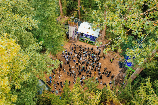 Herzogenaurach Germany 22 July 2022 Aerial view of the Open Beatz Festival stage nestled among lush green trees with a crowd of people dancing in the forest. Herzogenaurach Germany 22 July 2022 Aerial view of the Open Beatz Festival stage nestled among lush green trees with a crowd of people dancing in the forest.