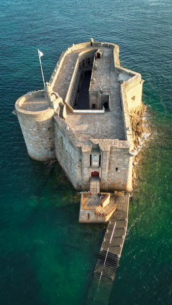 Aerial view of the Château du Taureau a stone fortress surrounded by the turquoise sea stands defiant against the crashing waves Plouezoc h Bretagne France. Aerial view of the Château du Taureau a stone fortress surrounded by the turquoise sea stands defiant against the crashing waves Plouezoc h Bretagne France.