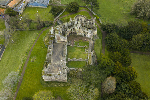 Aerial view of the medieval ruins of Dirleton Castle and Gardens surrounded by lush green lawns and mature trees in Dirleton Scotland United Kingdom. Aerial view of the medieval ruins of Dirleton Castle and Gardens surrounded by lush green lawns and mature trees in Dirleton Scotland United Kingdom.